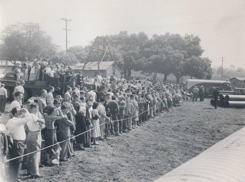 A crowd of locals held back by rope try to view the situation as police continue to search the well for three-year-old Kathy Fiscus.