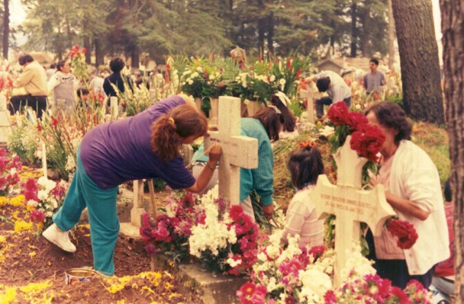 Mexican family tidying and decorating gravesites for Dia de Muertos at a cemetary in Almoloya del Rio, State of Mexico, Mexico | AlejandroLinaresGarcia/Wikicommons