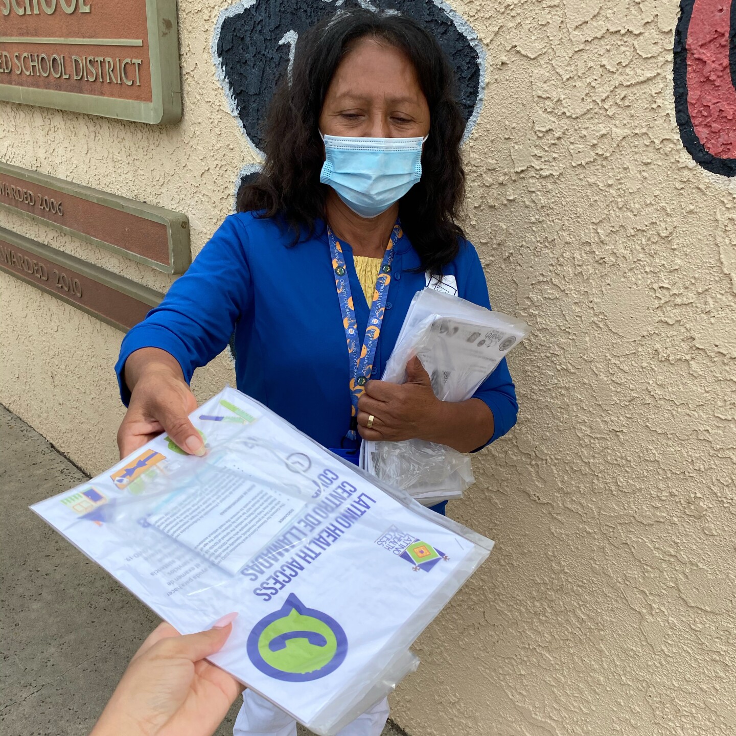 A woman in a face mask handing out coronavirus educational material.