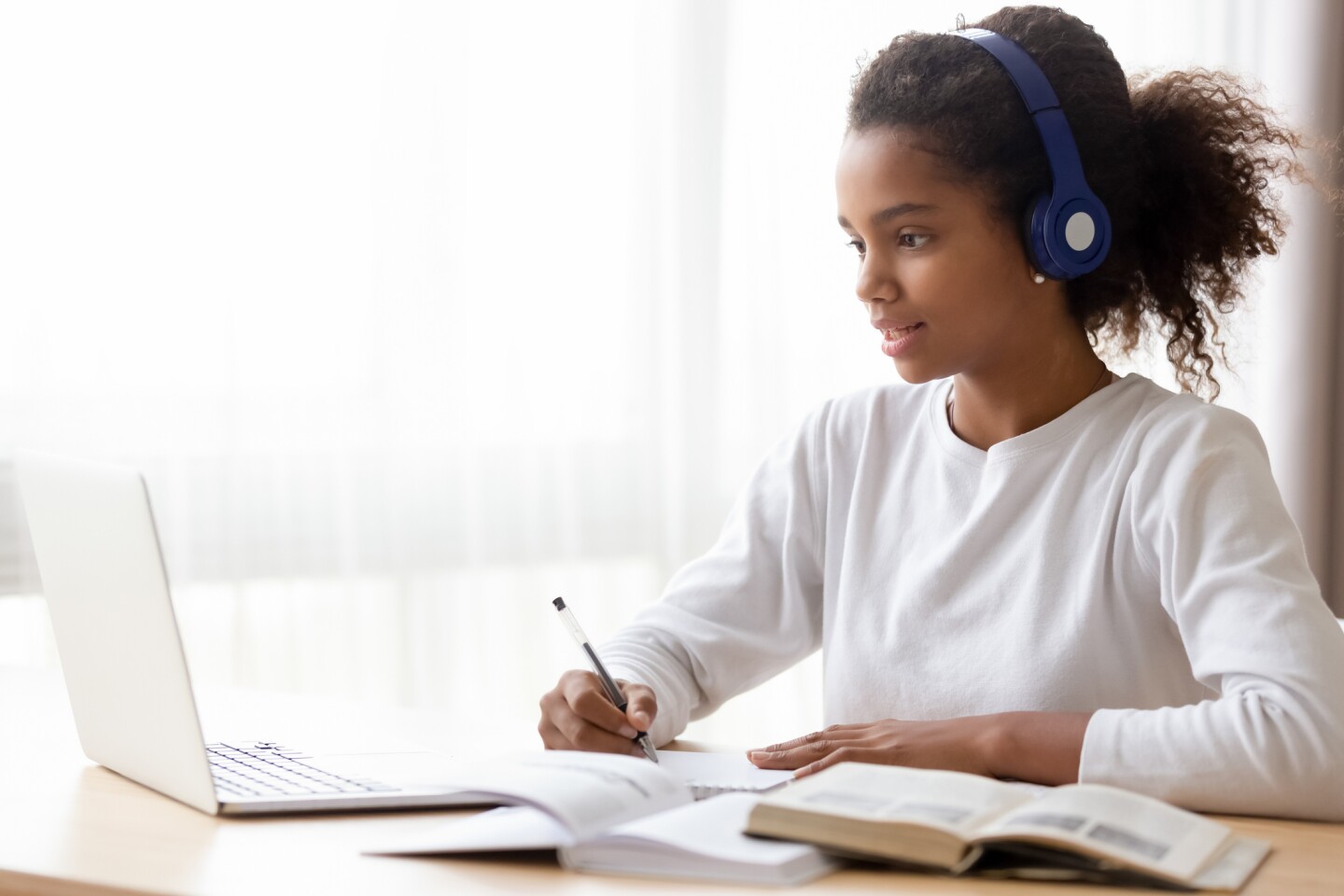 A young student wearing headphones and studying on a laptop.