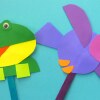 Un par de marionetas en forma de de rana y pájaro sobre un fondo azu