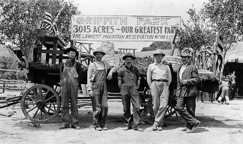 A group of men stand before a wagon and a painted banner with reads, "Griffith Park, 3015 acres — Our greatest park. The largest mountain reservation within a city." | UCLA, Library Special Collections, Charles E. Young Research Library