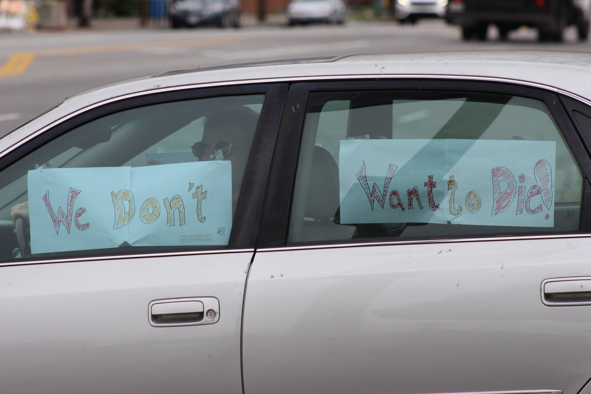 Signs reading "We don't want to die" taped to the inside of a car window, during protest at McDonalds on April 6, 2020 | Karen Foshay