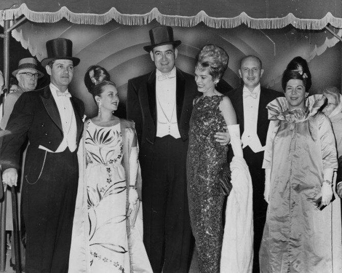 Beautifully gowned women and men wearing white ties, tails and top hats arrive at the Shrine Auditorium for the brilliant opening of the opera season. | Herald-Examiner Collection / LAPL Photo Collection