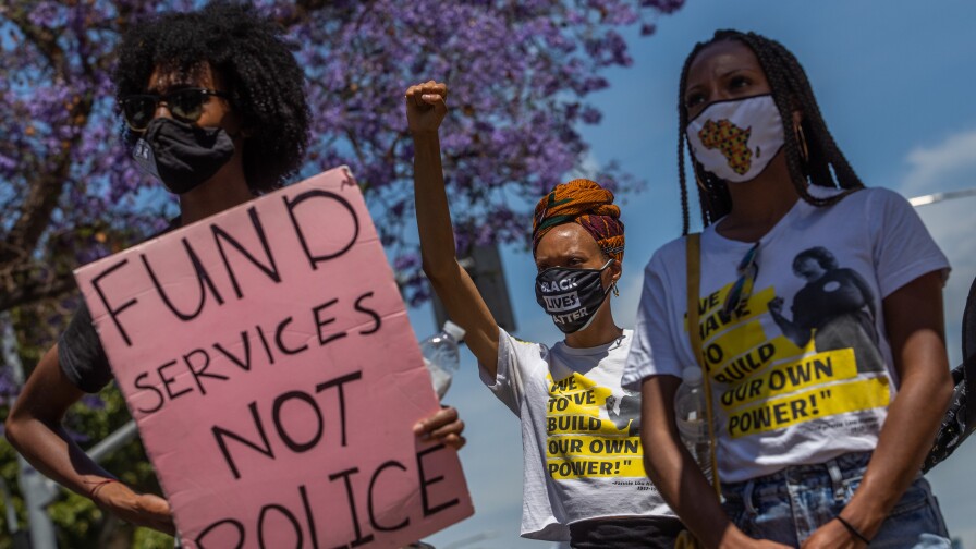 Protestors hold signs during a Black Lives Matter protest near The Los Angeles County Board of Supervisors building on the first anniversary of George Floyd's murder.
