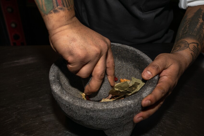 Chef Sanjay Rawat crushing spices using a mortar & pestle.