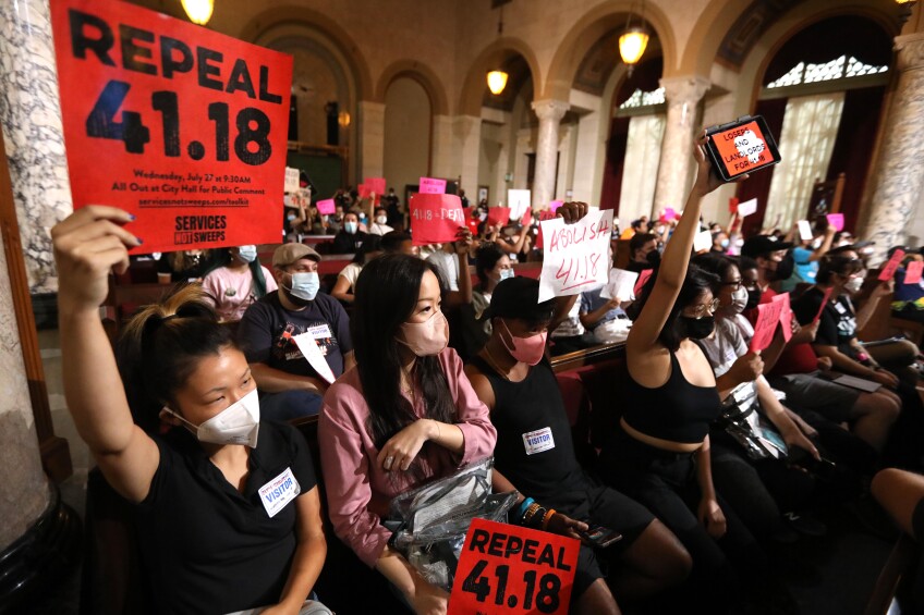 A group of spectators in the L.A. City Council chambers protest the vote on 41.18, a law banning homeless encampments