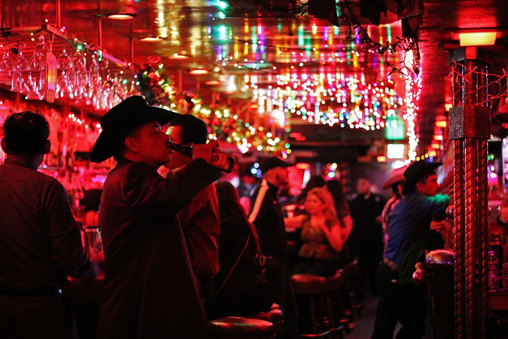 Scene from inside La Cita with men in hats and festive lighting. | Samanta Helou