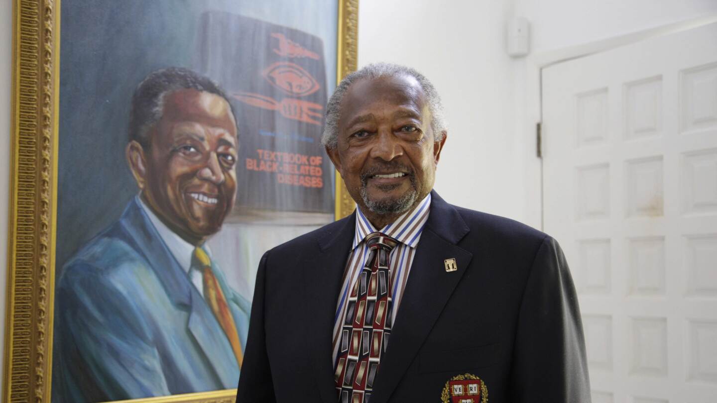 Dr. Richard Allen Williams stands beside a framed poster of his novel.