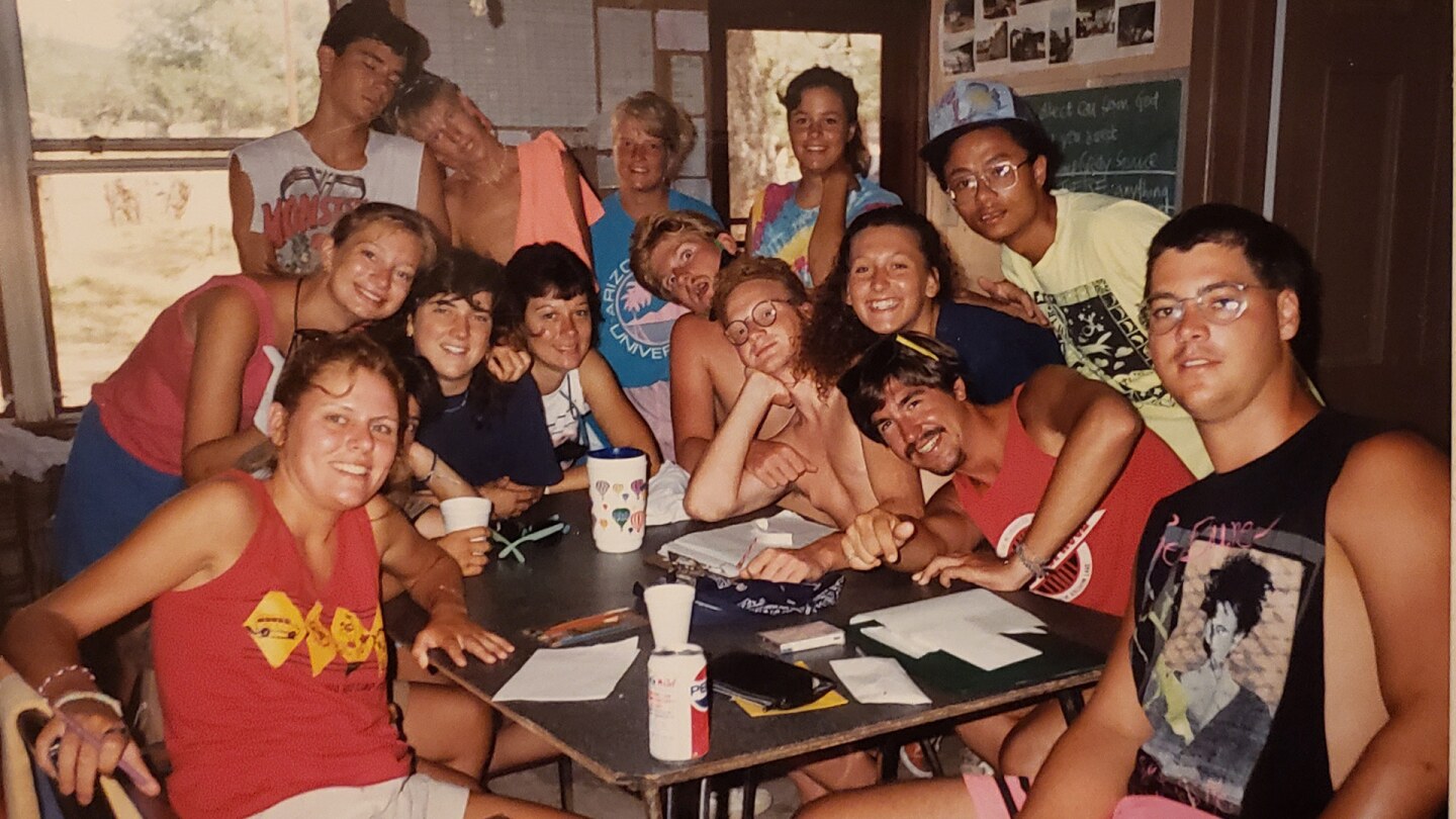 14 men and women sit together facing the camera
