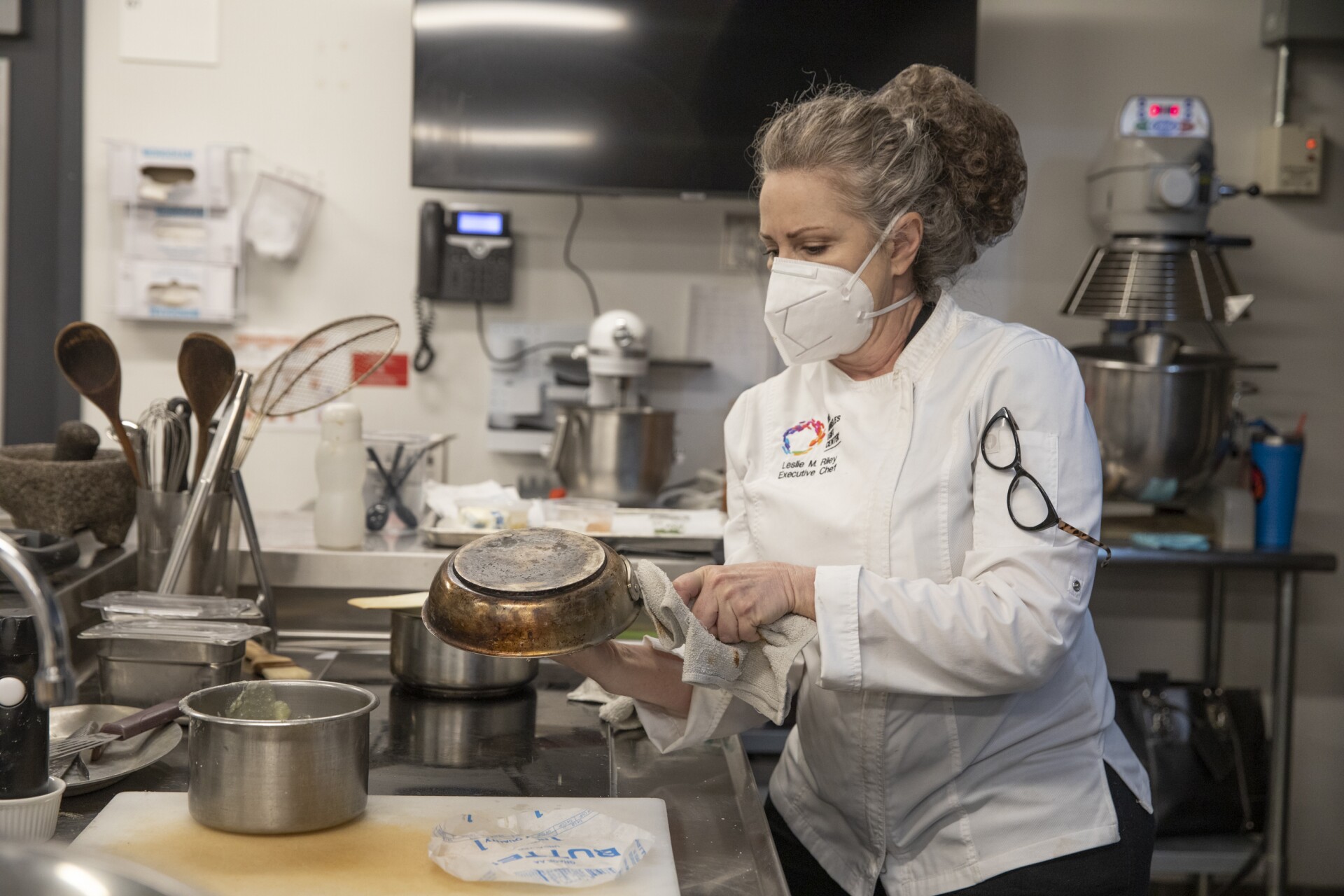 A woman with a mask is holding a pan.