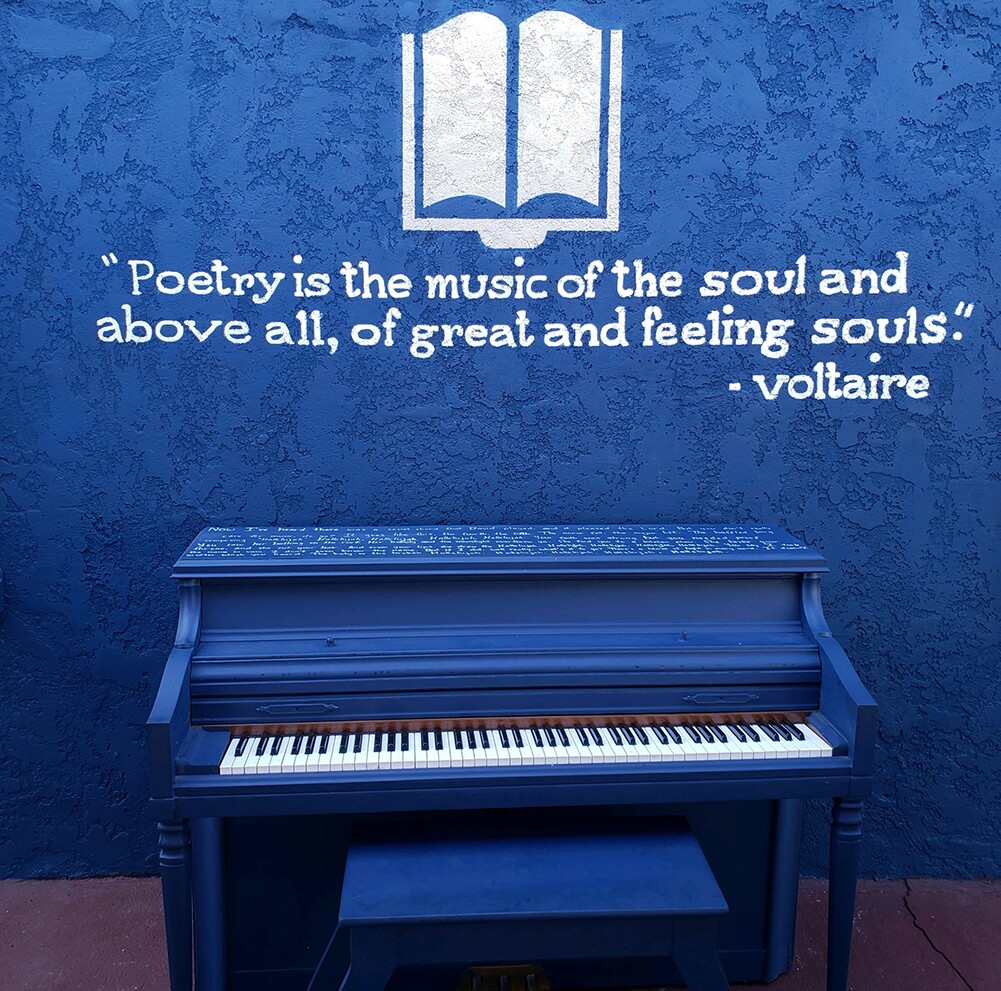 The striking patio at the Sims Library of Poetry features a blue piano with a quote from Voltaire. | Joshua Jones