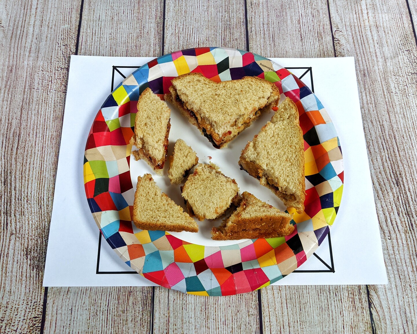A tangram made out of a cut up peanut butter and jelly sandwich.