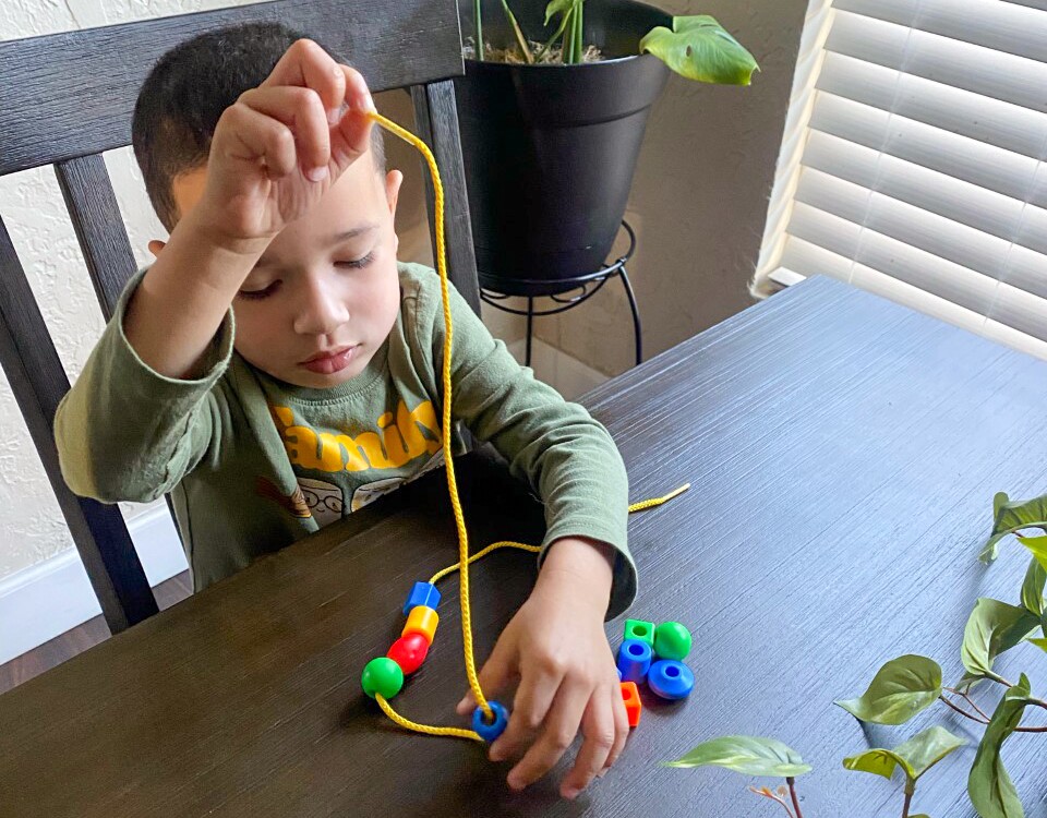 A child threads beads to make a bracelet