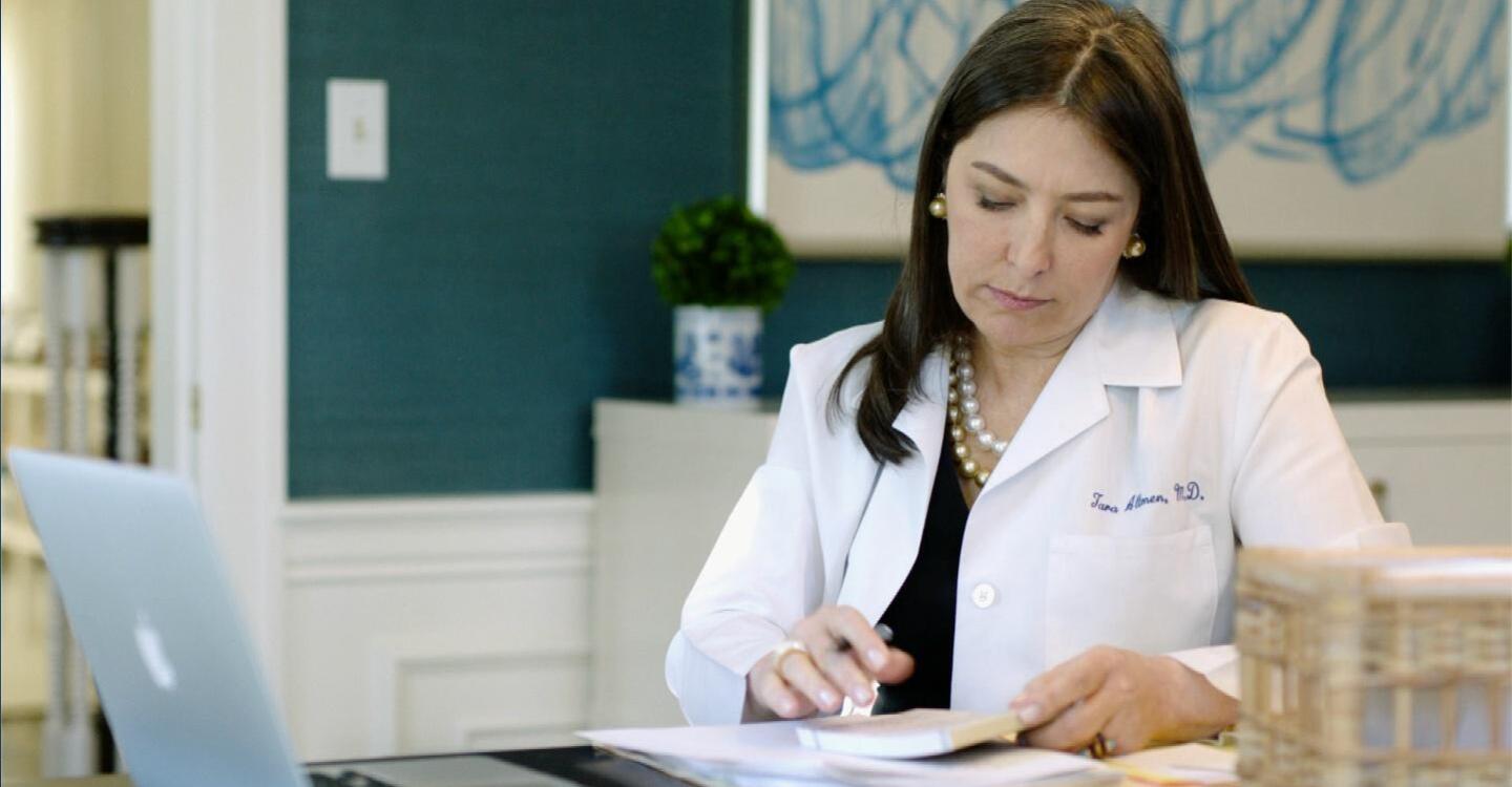 A doctor flips through her notes with a pen in her hand.