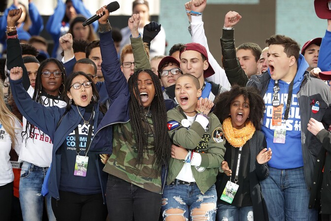 Students from Marjory Stoneman Douglas High School, including Emma Gonzalez (C), stand together on stage with other young victims of gun violence at the March for Our Lives rally on March 24, 2018 in Washington, DC. | Chip Somodevilla/Getty Images