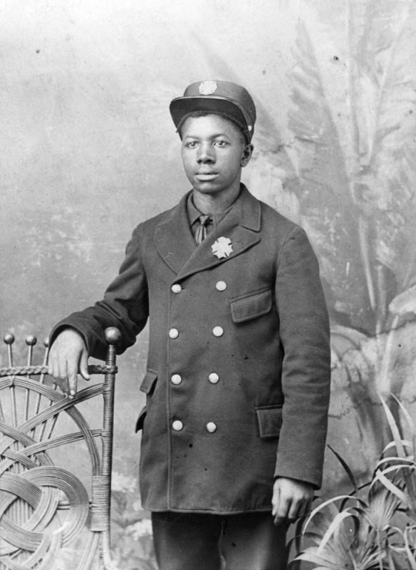 A portrait shot of a Black firefighter in uniform, photo is black and white