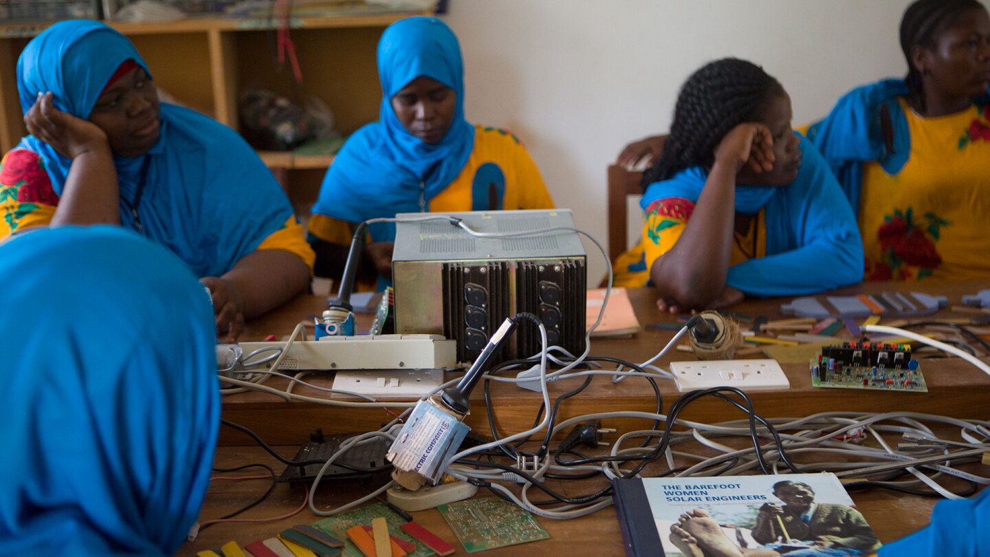 A group of women in Zanzibar sits at a table full of electric eqiupment. | Nicky Milne/Thomson Reuters Foundation