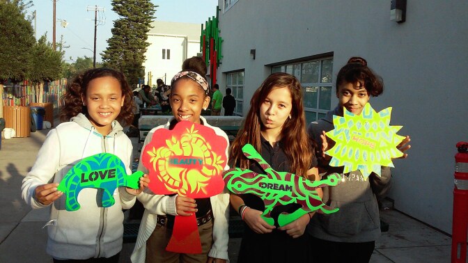 Three young girls pose with their contributions to an installation designed around the question: what sustains a community?