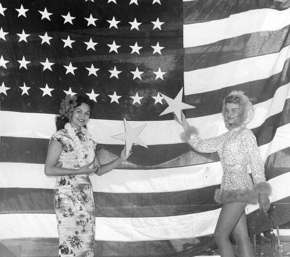 Women representing the newly-admitted states of Hawaii and Alaska hold up stars to the old 48-star U.S. flag at the Rose Bowl's 1959 July 4 celebration. Courtesy of the Hollywood Citizen News/Valley Times Collection, Los Angeles Public Library.
