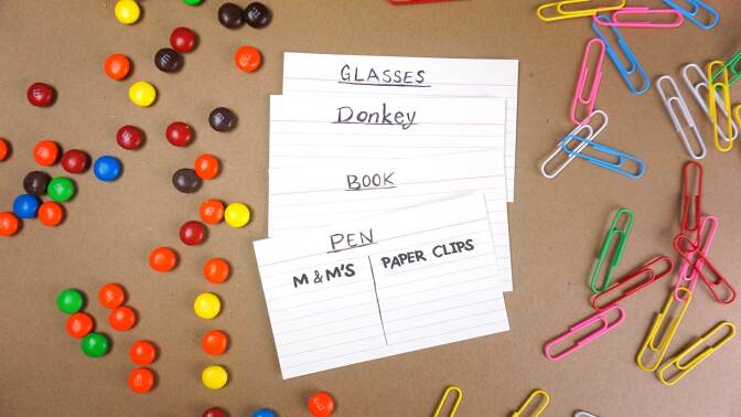 Several index cards (one for each item) are used to write down how much each thing measures in clips and candies.