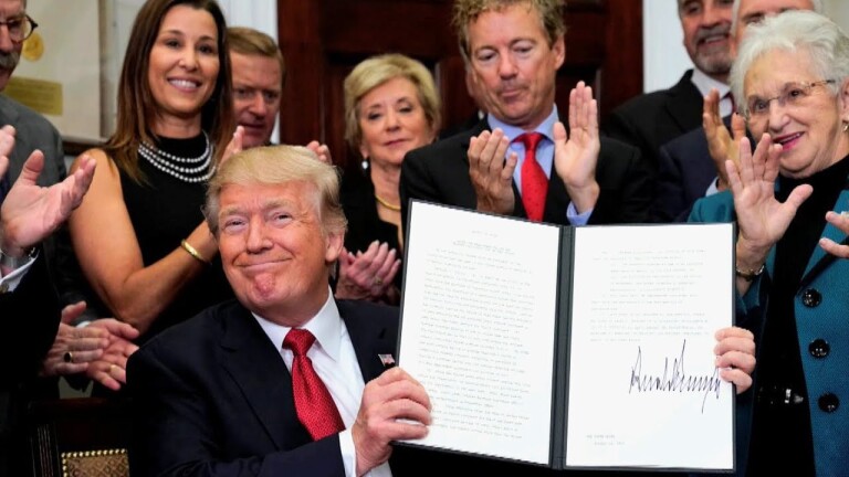 Trump displays an executive order signed by him to a cheering crowd. | Democracy Now