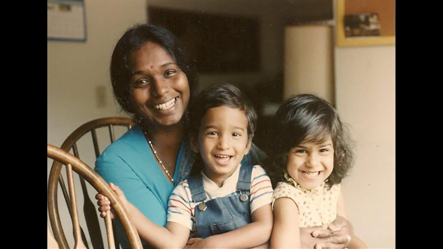 A woman sits hugging a little boy and girl.