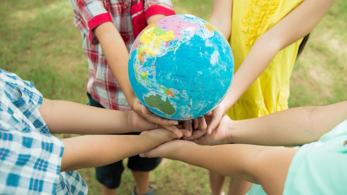 Cuatro niños sostienen un globo terráqueo.