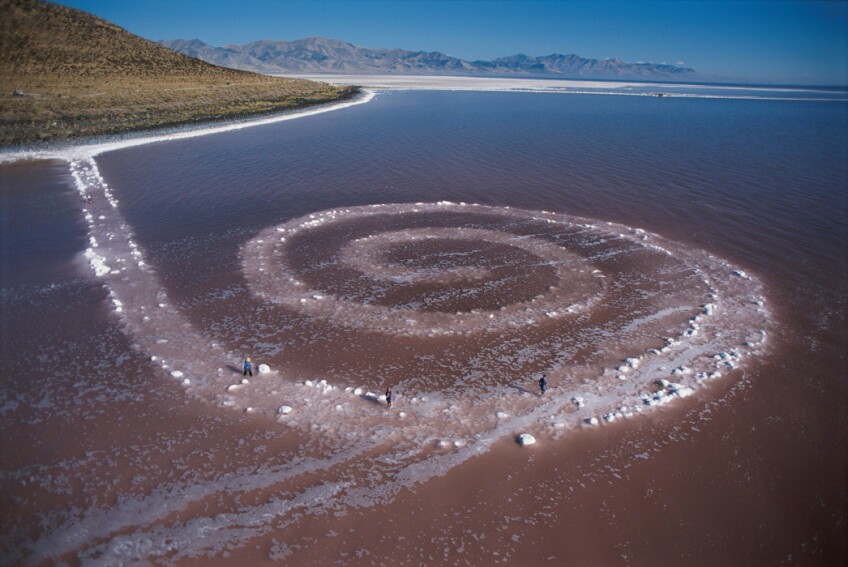 A view of Robert Smithson's land art called "Spiral Jetty" made primarily of black basalt rocks and salt crystals.