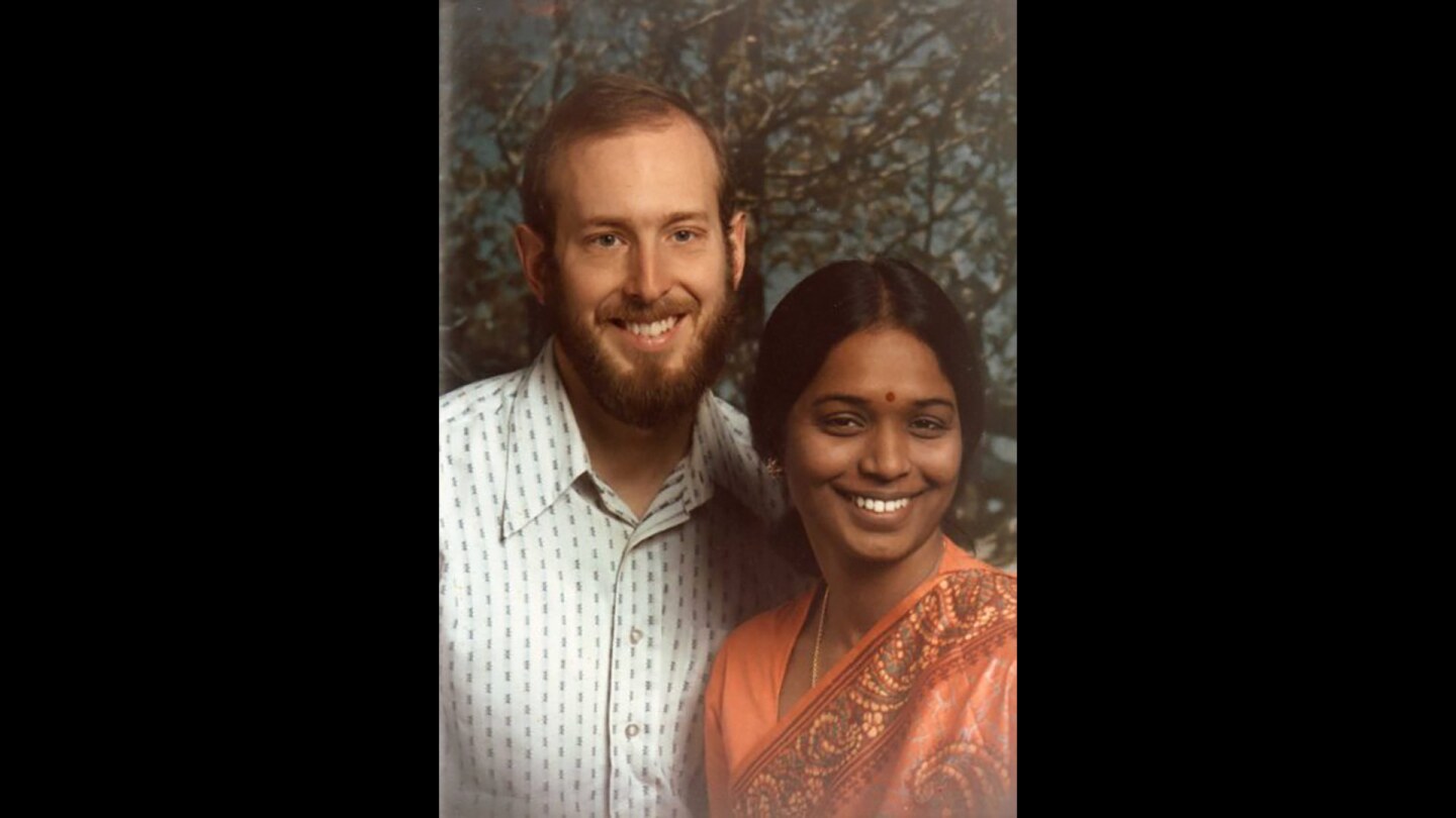 A woman in a sari with a bearded man, both smiling