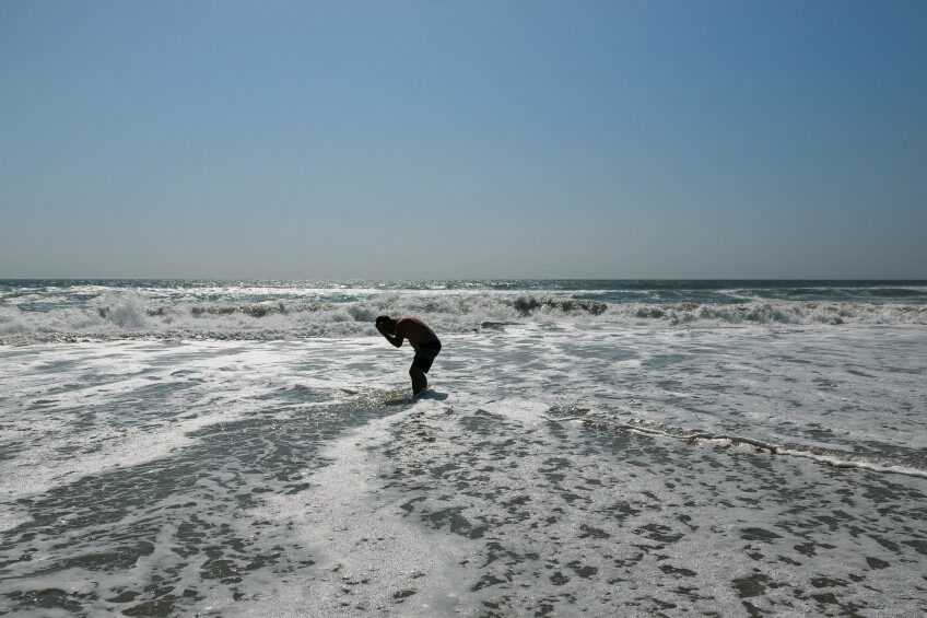 Albert Hernandez, 35, takes a break from his walk along the coast to splash fresh water on his face.