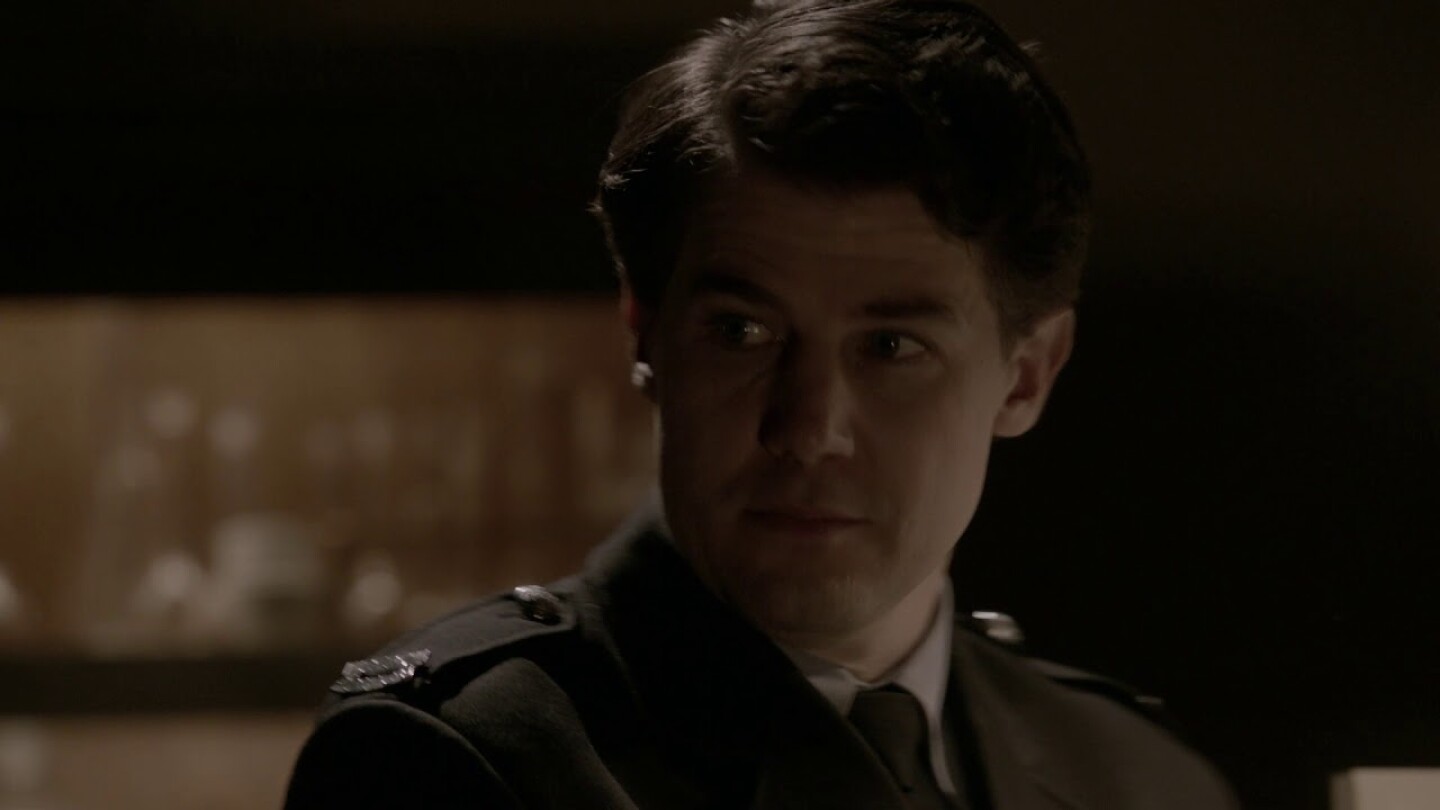Facial profile of man with brown hair wearing military jacket.