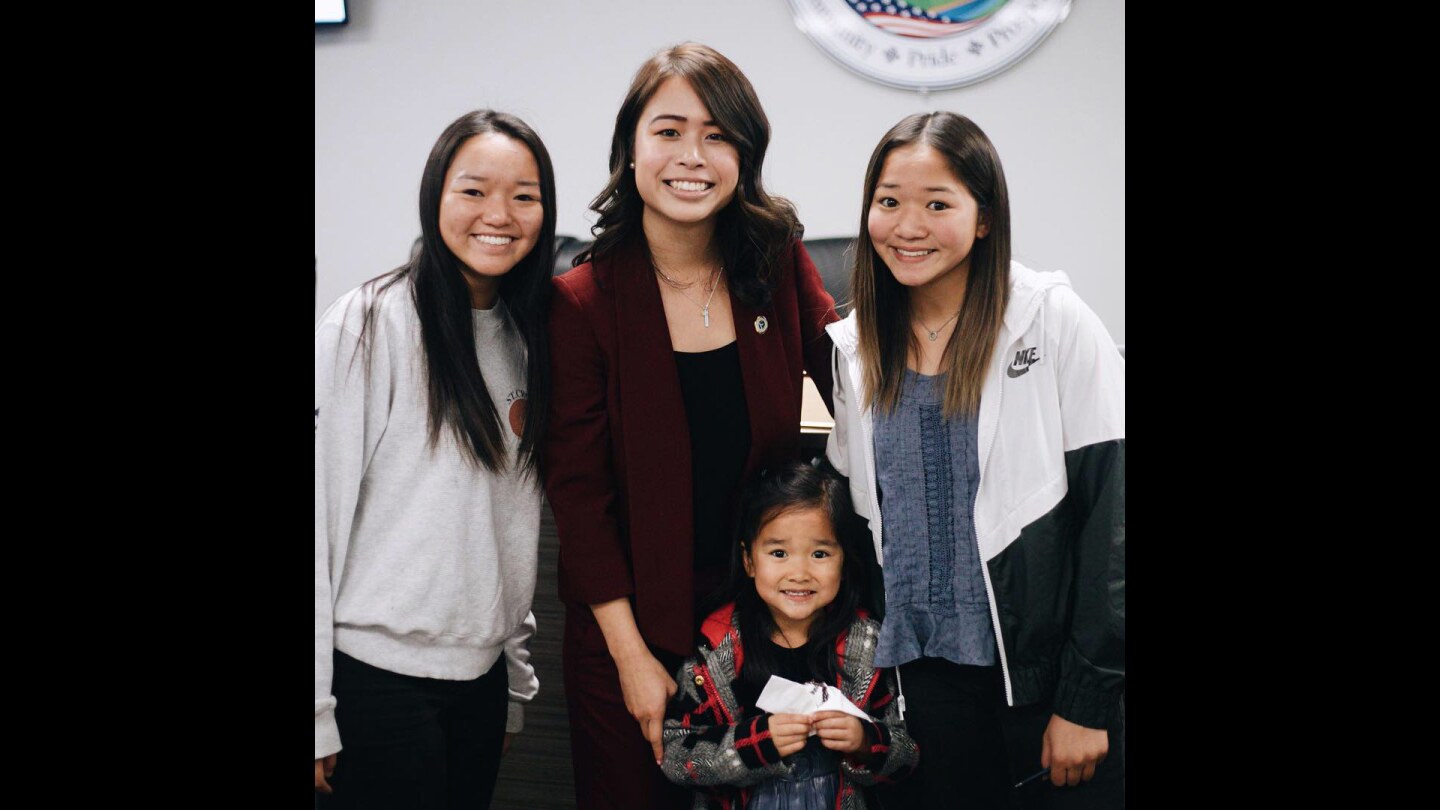 Three young women and a little girl stand together smiling at the camera