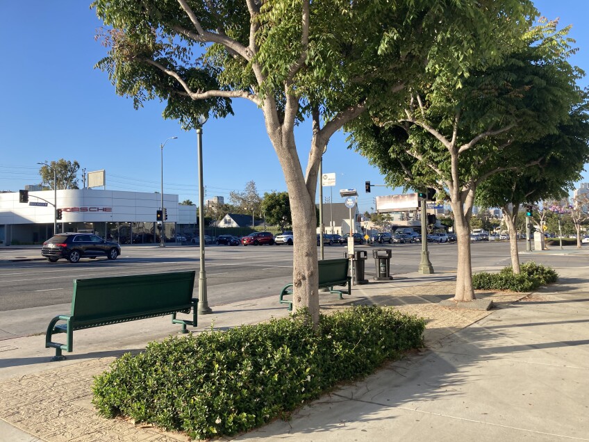 A bus stop on Santa Monica Boulevard features benches and tree shade