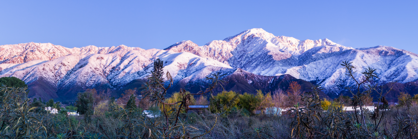 A mountain range, parts of which are covered in snow.