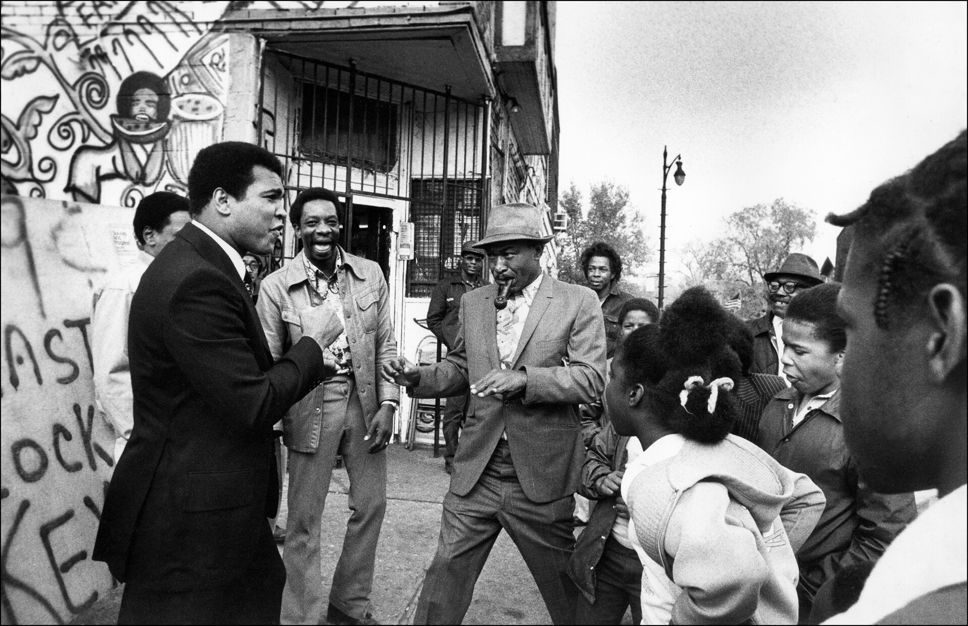 A Black man is surrounded by children and adults.
