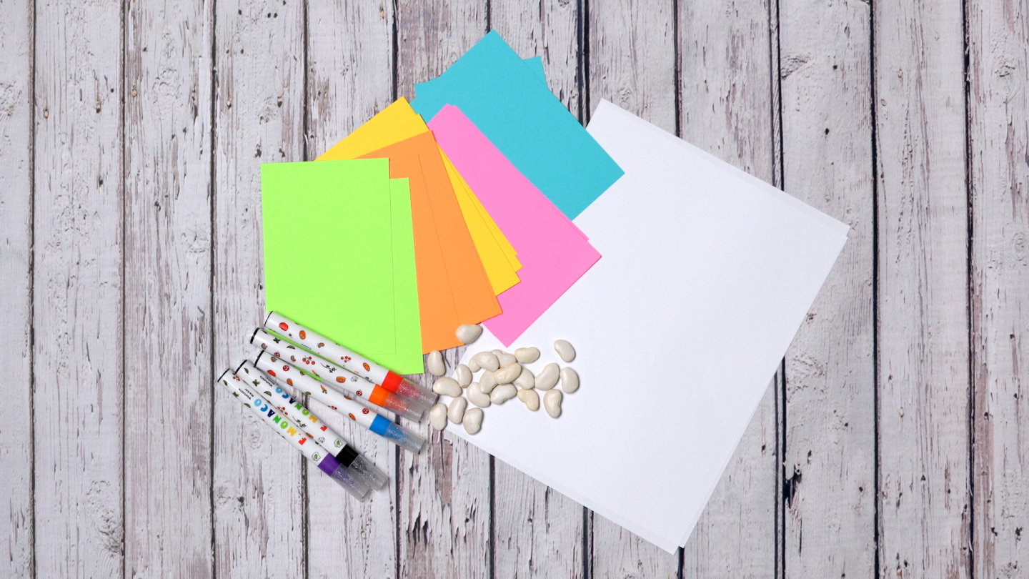 Markers, dry beans, a sheet of paper and colorful index cards are laid out on a table