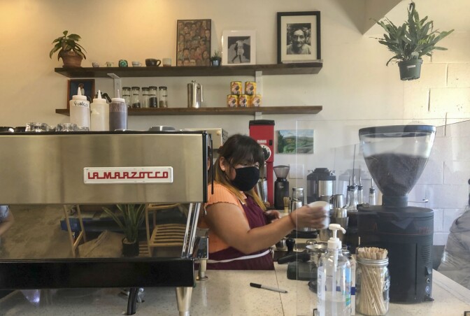 A barista prepares a coffee drink behind the counter.