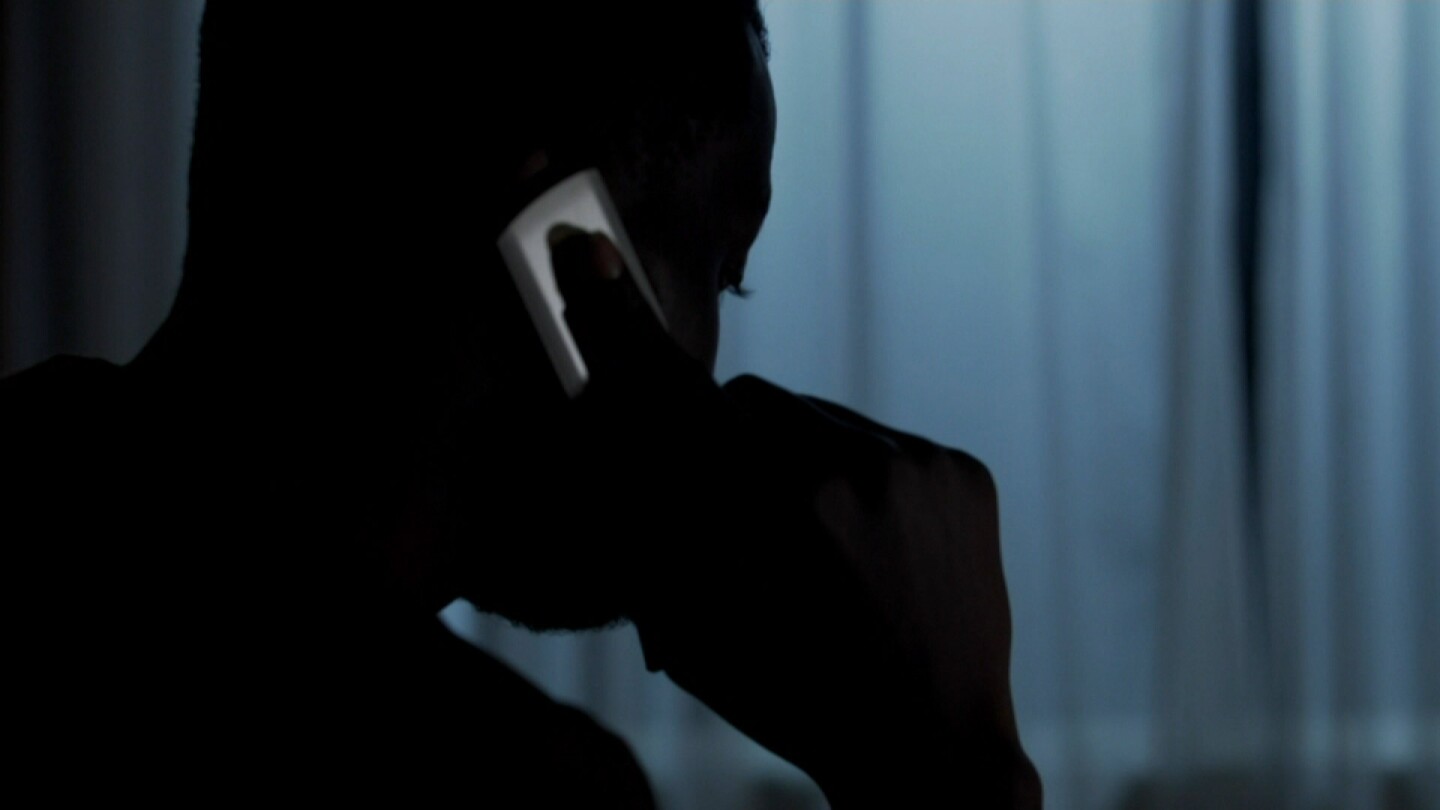 Silhouette of a person involved in a scam. | Still from "Four Corners" episode "Meet the Scammers"
