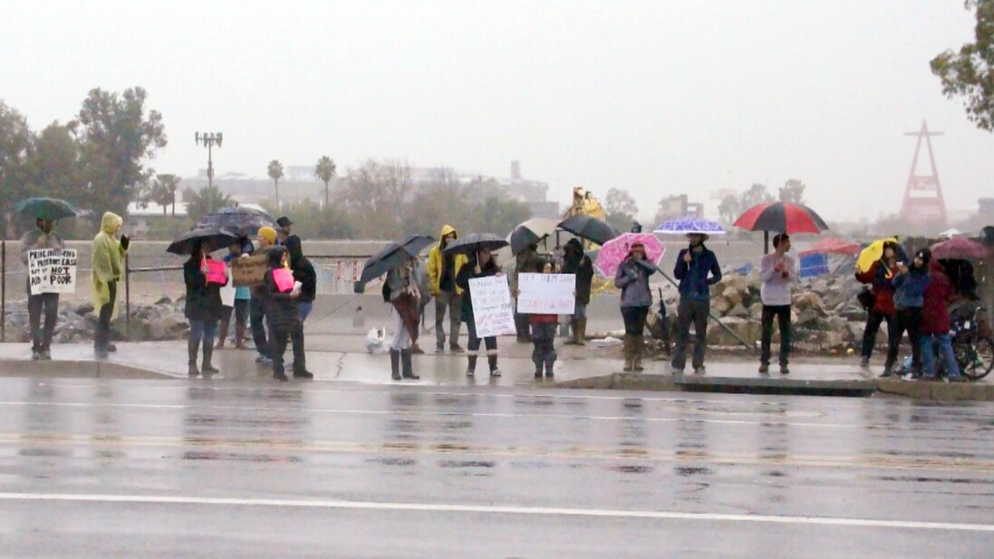 Demonstrators hold signs along Chapman Ave. next to the Santa Ana River | photo by Nick Gerda/Voice of OC