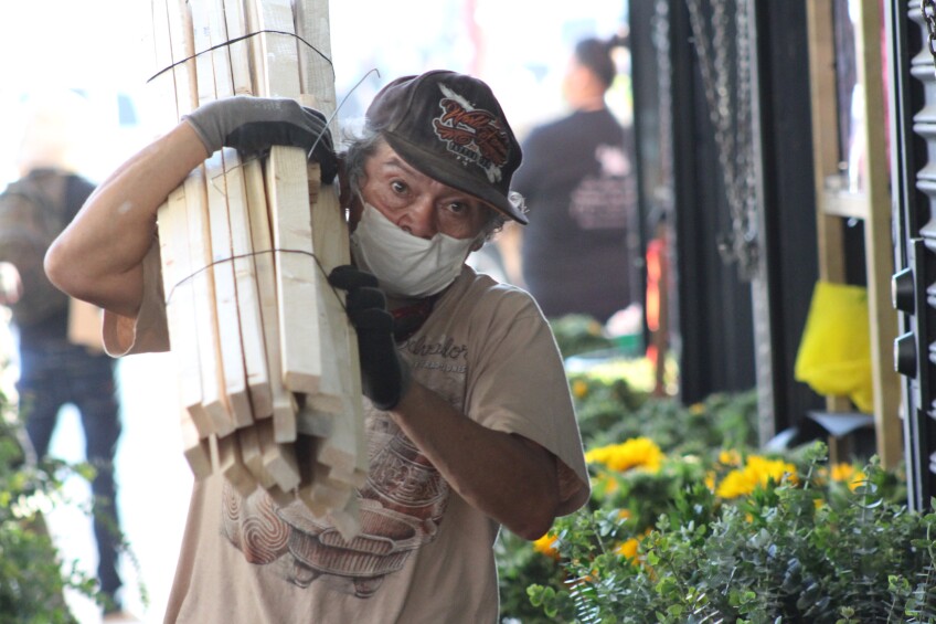 Man carries wood over his shoulder at Flower Market, as it reopened on May 8, 2020 | Karen Foshay