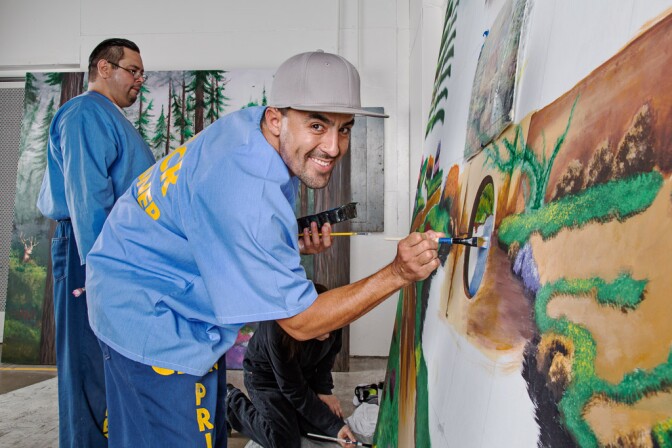 A prison inmate paints a mural as part of a Project PAINT art workshop at Richard J. Donovan Correctional Facility in San Diego