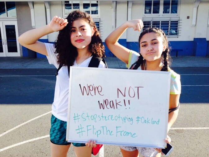Two young women hold out a sign that says "We're not weak" as part of the “Flip the Frame” campaign to “transform policies, practices, and perceptions” and challenge the damaging assumptions imposed on Black and Brown youth. | Californians for Justice