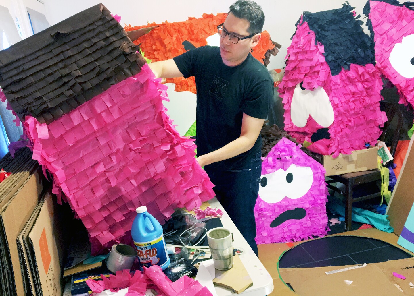 A young man wearing a black shirt working on piñatas.
