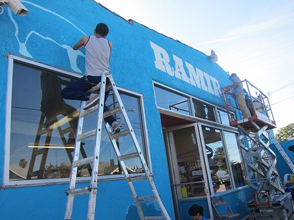 School of Communications, New Media + Technology (CNMT) at Roosevelt High School student Diego Garcia painting the exterior of Ramirez Meat Market, the 2nd transformed Proyecto MercadoFRESCO East L.A market.
