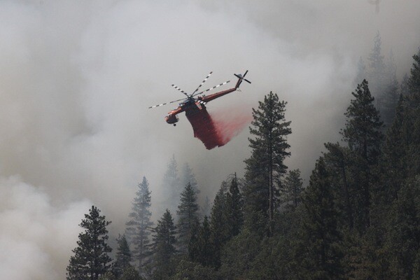 A helicopter assists fire crews on the ground. | Photo: Sean Collins/Inciweb