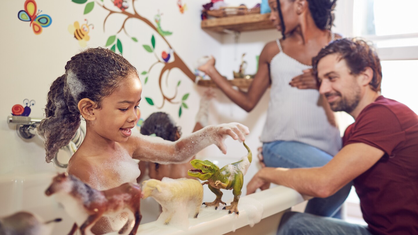 Pregnant parents giving daughters bubble bath