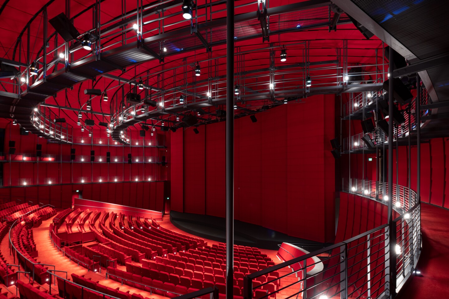 An interior image of the David Geffen Theater at the Academy Museum of Motion Pictures. The seats, walls and flooring are all a deep red color.