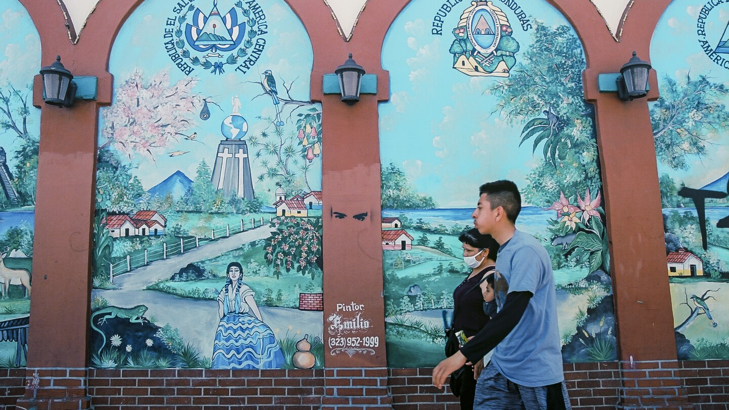 A family walks past a mural of the different Central American countires.
