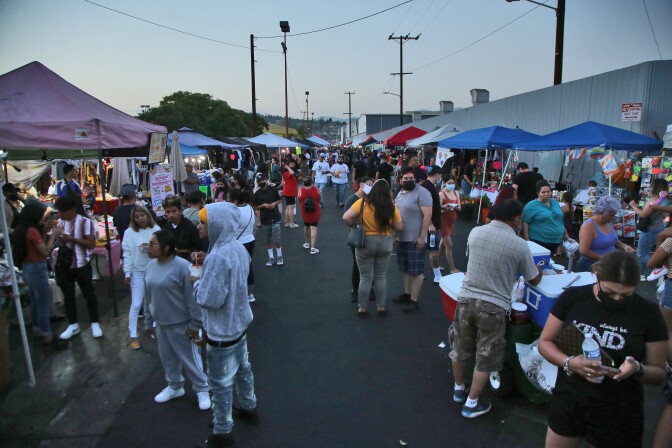 Crowds gather along a row of street food tents.